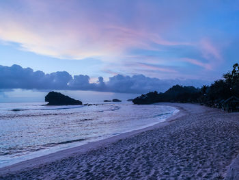Scenic view of watukarung beach against sky at sunset