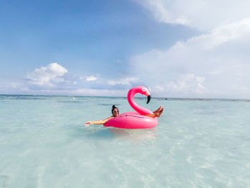 Young woman floating in inflatable ring on sea against sky