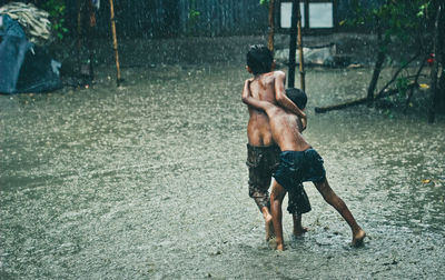 Rear view of shirtless man standing in water