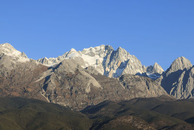 Low angle view of snowcapped mountains against clear blue sky