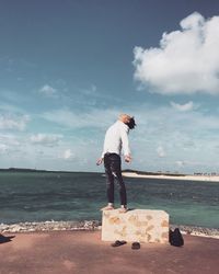 Man standing on beach against cloudy sky