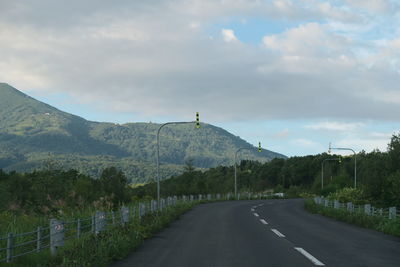 Road by mountains against sky
