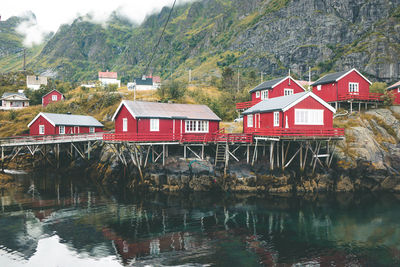 Red houses by lake and buildings against trees in norway