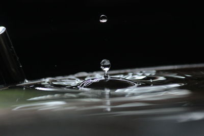 Close-up of drop falling in container at night