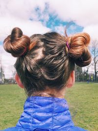 Rear view of girl on field against sky