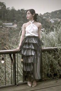 Young woman standing by railing