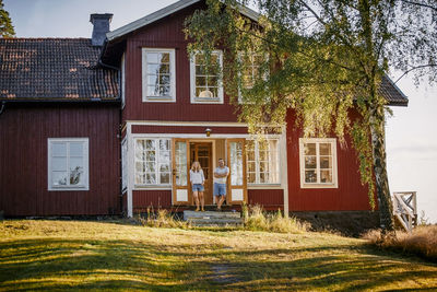 Mid distant view of couple standing on entrance of house in summer