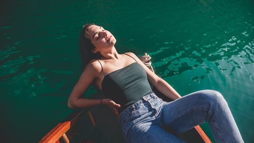 Young woman sleeping in boat on lake