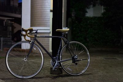 Bicycle parked on footpath against building