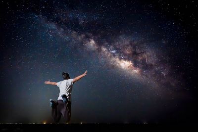 Full length of man jumping against star field at night