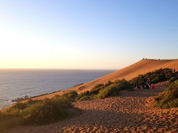 Scenic view of beach against clear sky during sunset