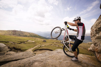 Man performing wheelie on mountain against sky