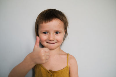 Cute child in yellow  jumpsuit shows hand like, hand thumb up. light background