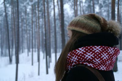 Woman wearing hat in forest during winter