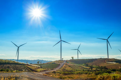 Windmill on road against blue sky