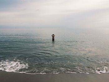 Man in sea against sky