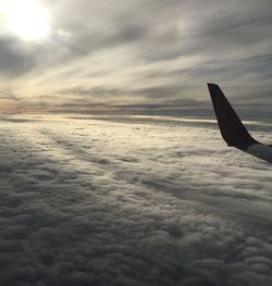 Airplane flying over sea against sky during sunset