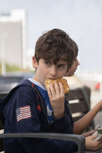 Portrait of a kid looking away stunned or surprised while eating a pancake in a park bench