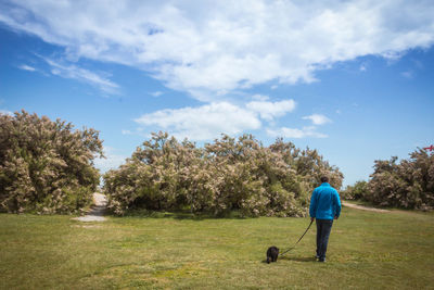 Rear view of man with dog walking in park