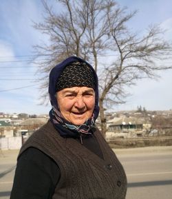 Portrait of senior woman wearing warm clothing against sky in city