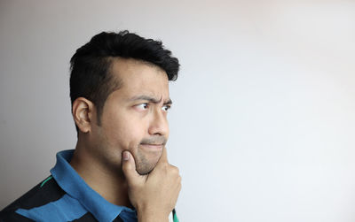 Portrait of young man looking away against white background