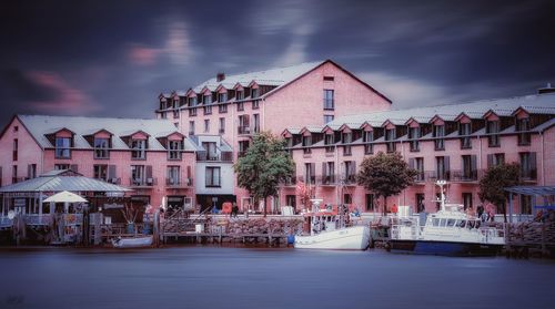 Buildings by river against sky in city