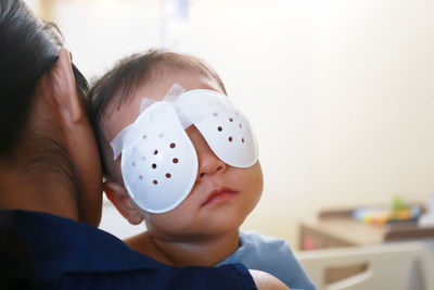 Close-up of mother carrying baby boy with bandage on eyes