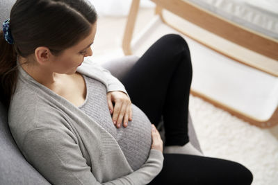 Side view of woman sitting on sofa at home