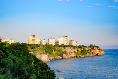 Buildings by sea against blue sky