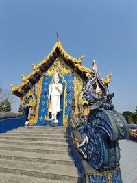 Low angle view of statue against blue sky and building