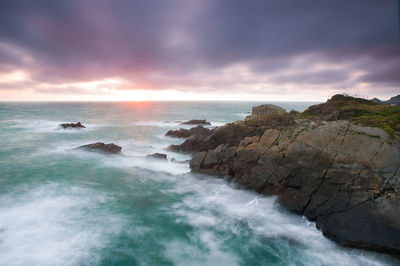 Scenic view of sea against cloudy sky during sunset