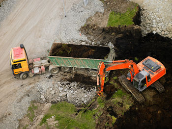 Aerial shot of earth mover filling dump truck at building site