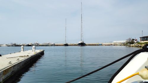 Sailboats moored at harbor against sky