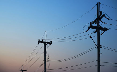 Low angle view of electricity pylon against clear blue sky