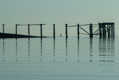Reflection of pier in sea against clear sky