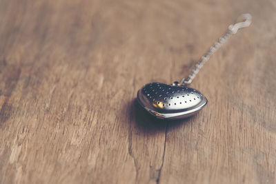 Close-up of chain with metallic heart shape pendant on wooden table