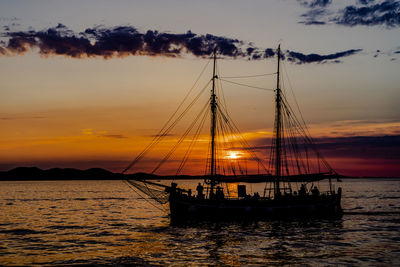 Silhouette sailboat sailing on sea against sky during sunset