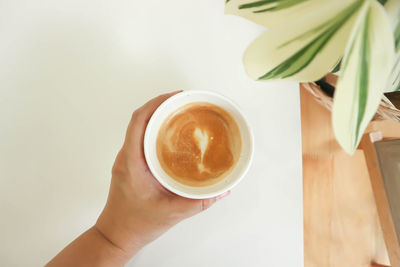 Cropped image of hand holding coffee cup on table