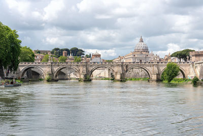 Arch bridge over river against buildings in city