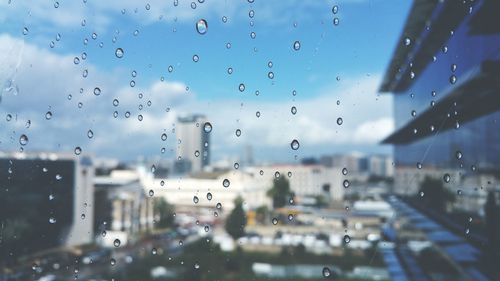 Water drops on glass against blurred buildings