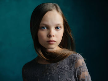 Portrait of teenage girl against blue background