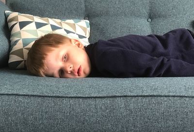 Close-up of cute boy lying on sofa at home