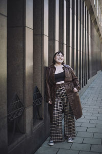 Portrait of young woman standing against building