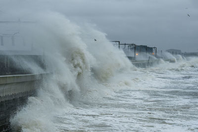 Waves splashing in sea against sky