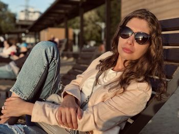 Portrait of young woman wearing sunglasses sitting outdoors