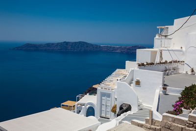 Buildings by sea against blue sky