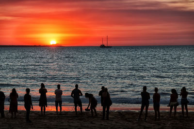 Group of people on beach during sunset