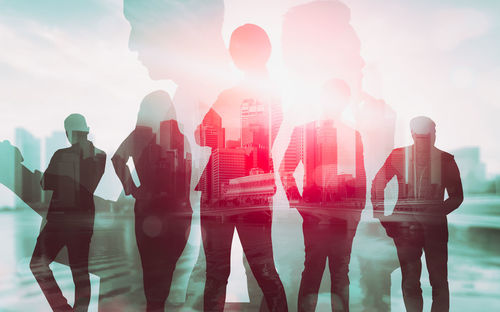 Digital composite image of silhouette people standing in city against sky