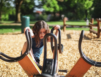 Caucasian beautiful girl climbs on a spinning swing in the park at the playground