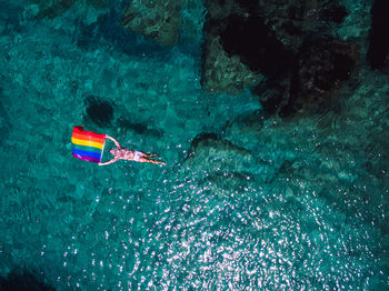 Aerial view of man swimming with rainbow flag